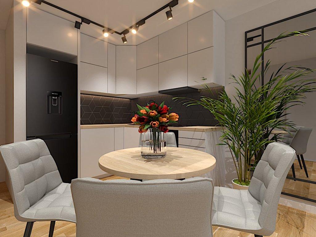 Projekt salonu z jadalnią i kuchnią Wrocław na wizualizacji widzimy aranżację kuchni w stylu nowoczesnym gdzie dolne i górna szafki są białe, blat drewniany, a na ścianie pomiędzy szafkami czarne płytki, stół w jadalni jest okrągły, krzesła szare tapicerowane na suficie jest szynoprzewód z refrektorami